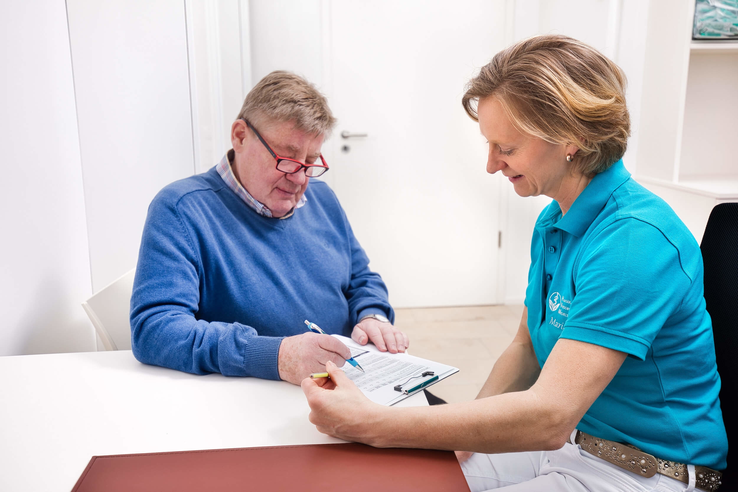 Ärztin hilft einem Patient Dokumente auszufüllen